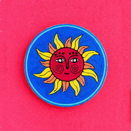 Handmade Huichol yarn painting showing the Sun God with a red face and yellow rays, crafted with yarn and beeswax on a 15cm round wooden base. Front Image