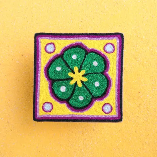 Front view of a handmade Huichol yarn painting showing a green peyote design on a 10cm square wooden base.