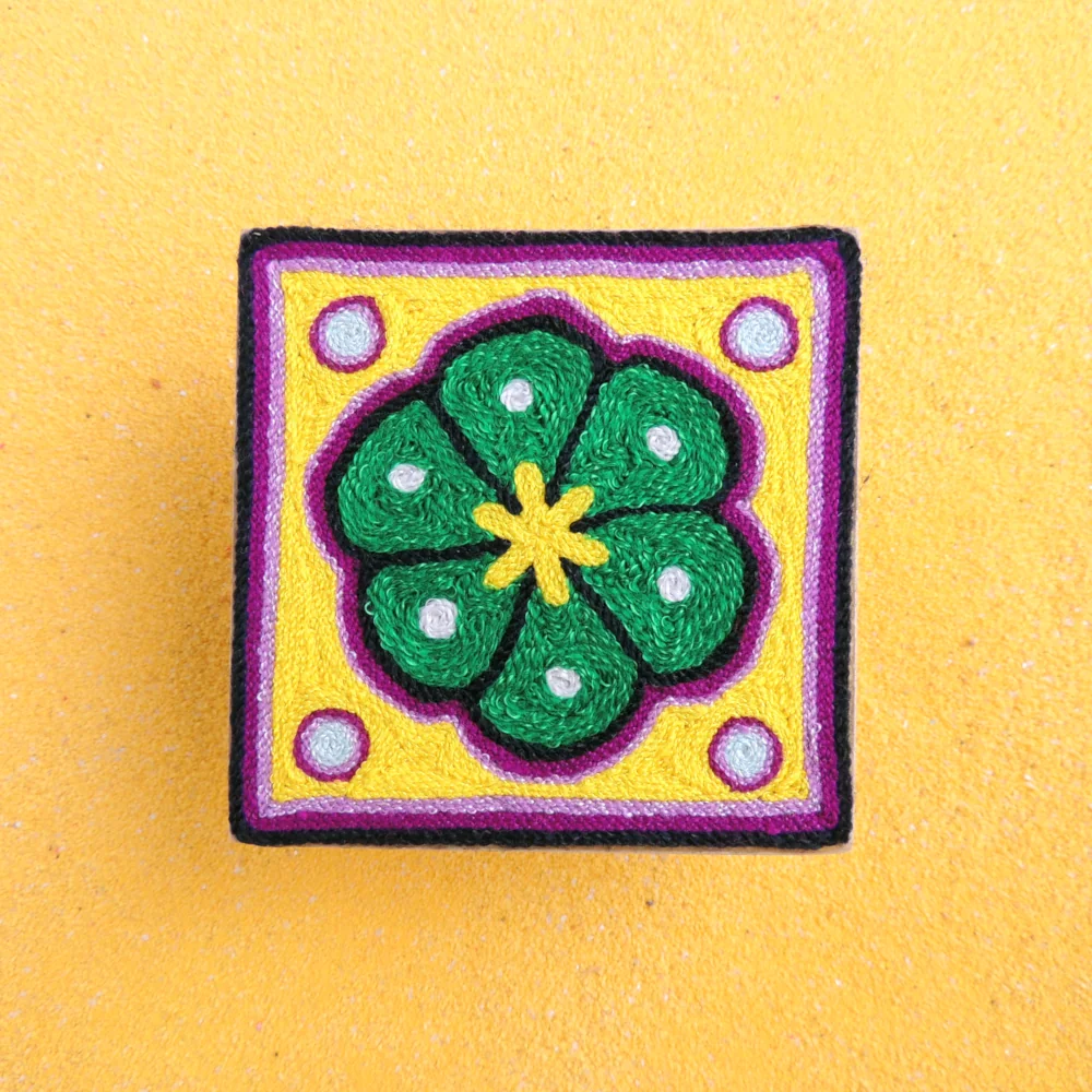 Front view of a handmade Huichol yarn painting showing a green peyote design on a 10cm square wooden base.