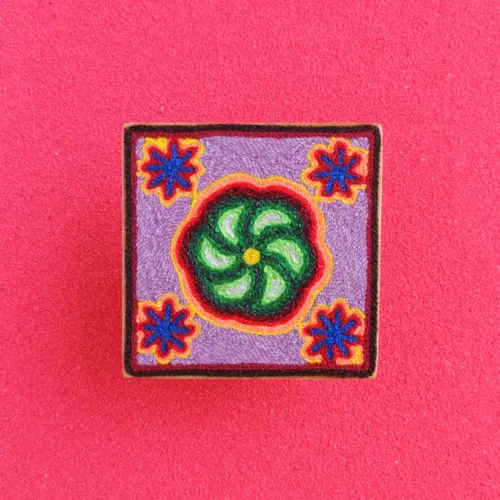 Front view of a handmade Huichol yarn painting showing a green peyote design with blue flower shapes on a 10cm square wooden base