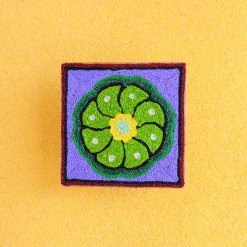 Front view of Huichol yarn painting with green peyote on a 10cm square base.