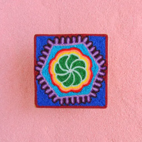 Front view of Huichol yarn painting with green peyote and layered colors.