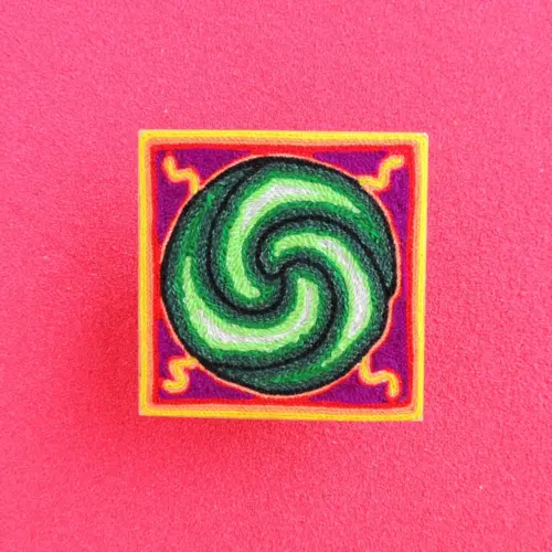 Front view of a 10 cm Huichol yarn painting with a green peyote spiral