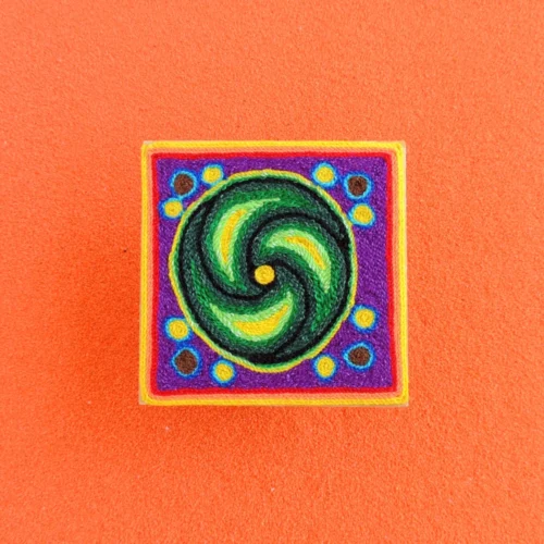 Front view of a 10 cm Huichol yarn painting with a green peyote swirl and dots